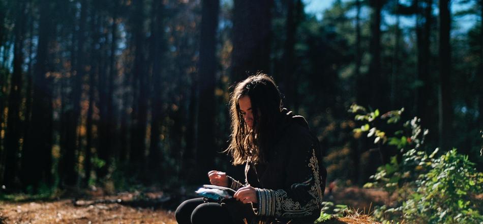 woman writing in journal over the woods